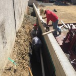 Installation of drainage system behind east retaining walls. This system is to channel any water that collects behind the wall to a site drainage line.